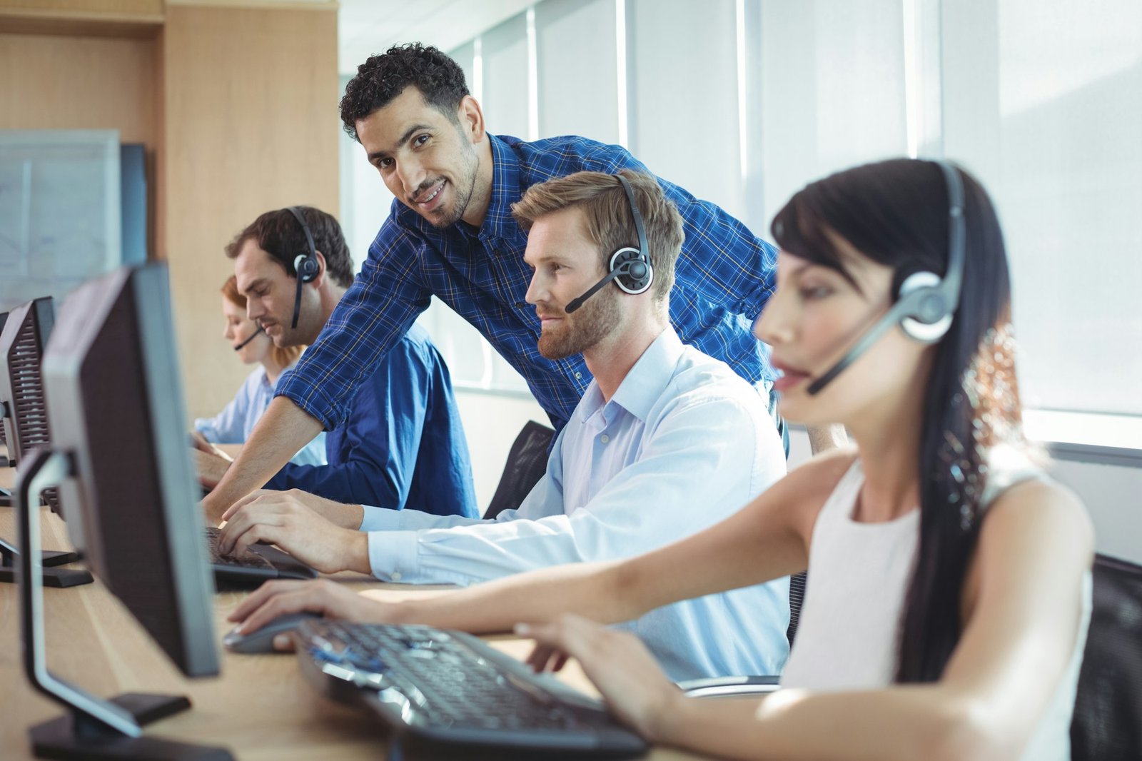 Male supervisor assisting telemarketer at call center